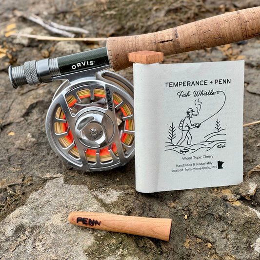 Wooden Pipe with Product Packaging Next to a fly Fishing Pole
