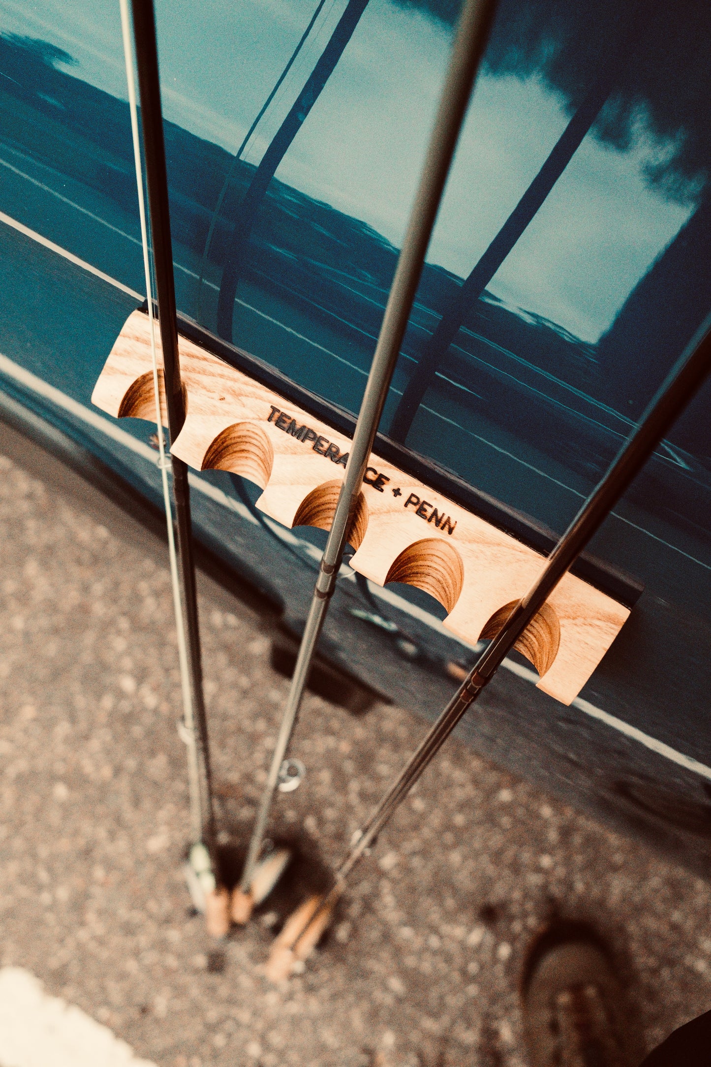 Close-up of three fishing rods securely held by a CastHitch magnetic rod holder attached to a vehicle, showcasing the durable grip and compact design for convenient rod storage.