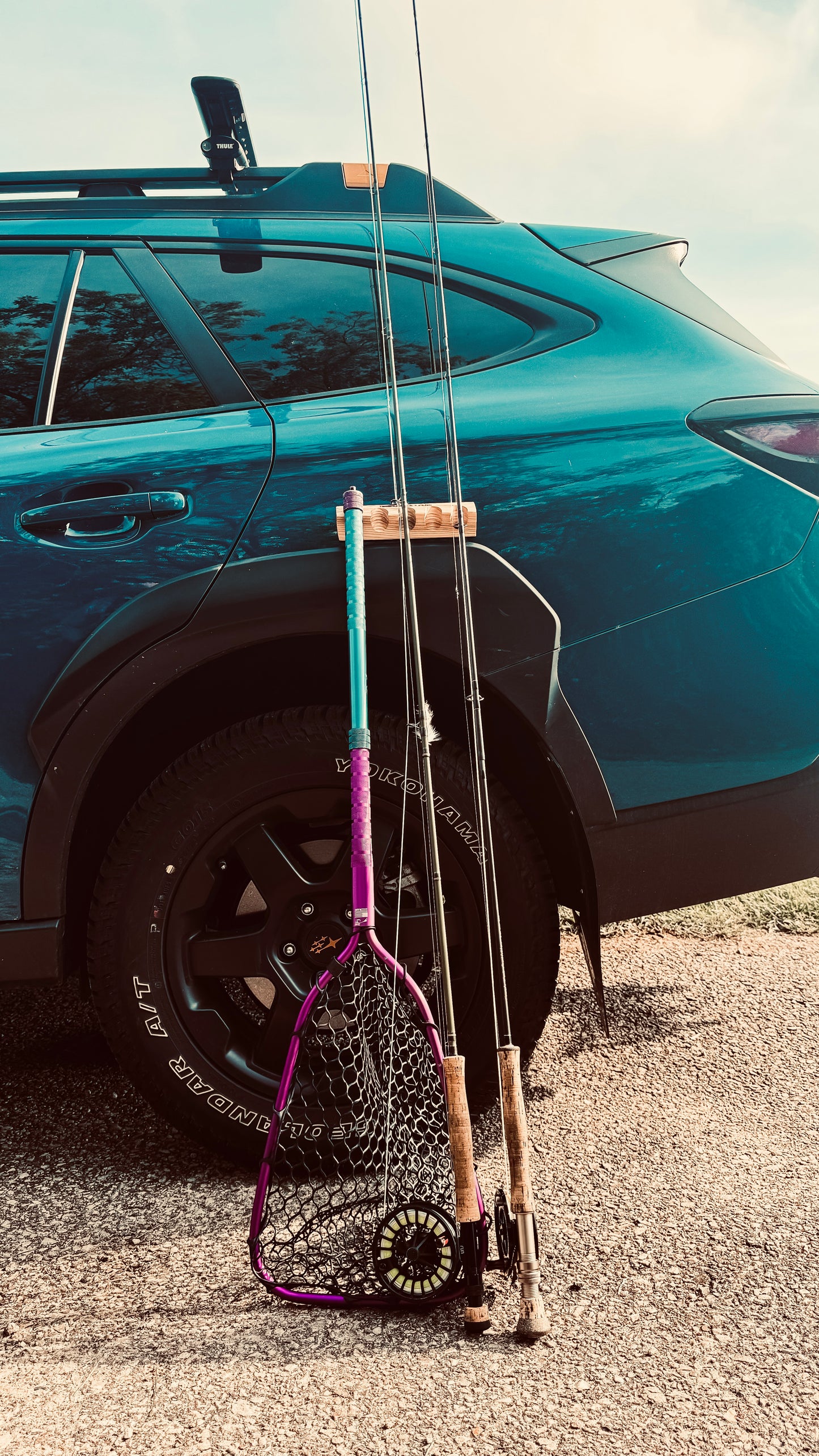 Close-up of two fishing rods and fishing net securely held by a CastHitch magnetic rod holder attached to a vehicle, showcasing the durable grip and compact design for convenient rod storage and the versatility beyond fishing rod storage