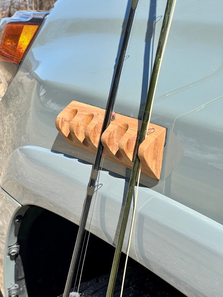 Close-up of two fishing rods securely held by a CastHitch magnetic rod holder attached to a vehicle, showcasing the durable grip and compact design for convenient rod storage.