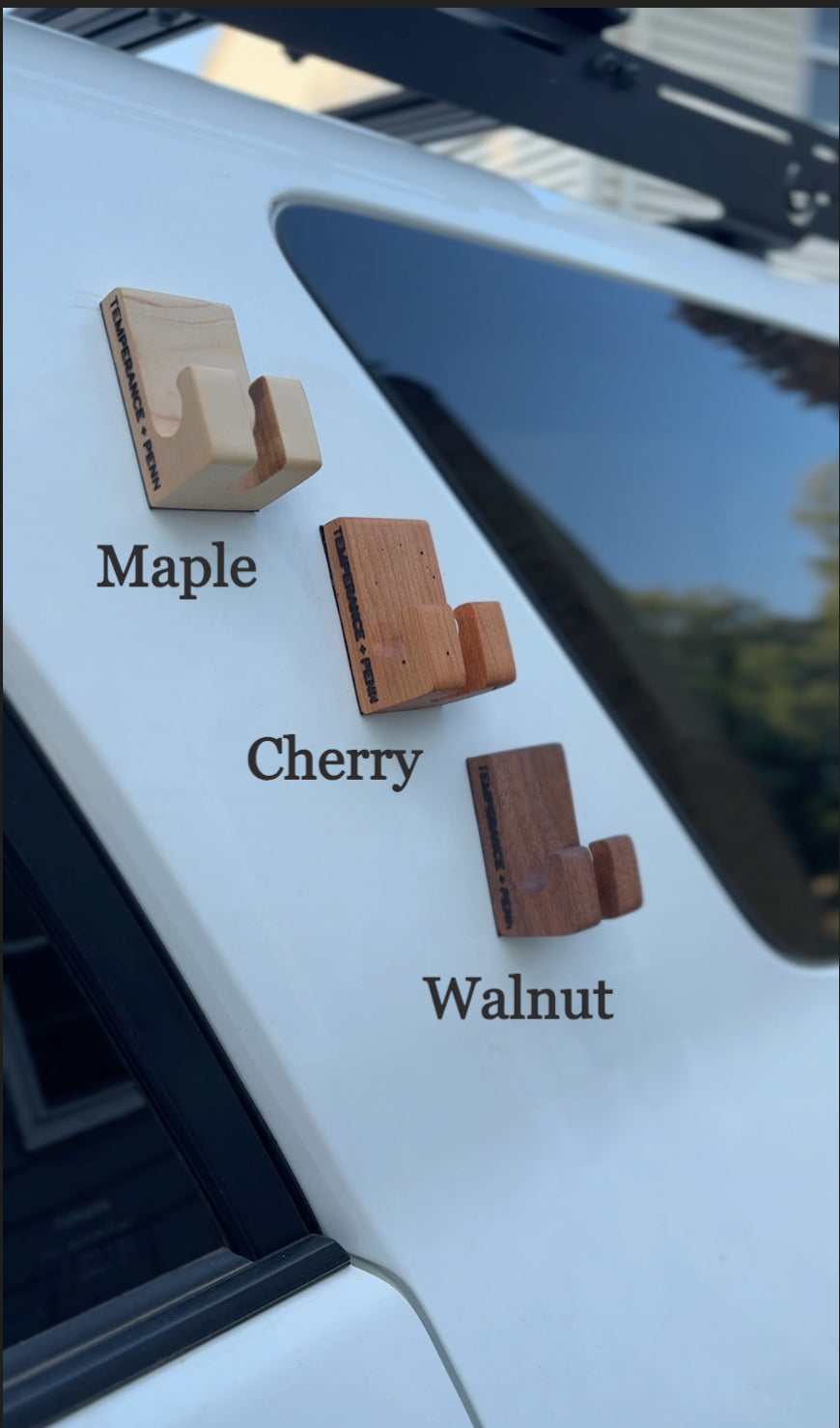 GearHook magnetic holder closeup attached to a vehicle, showing 3 different gearhooks - Maple hardwood, Cherry Hardwood and Walnut Hardwood