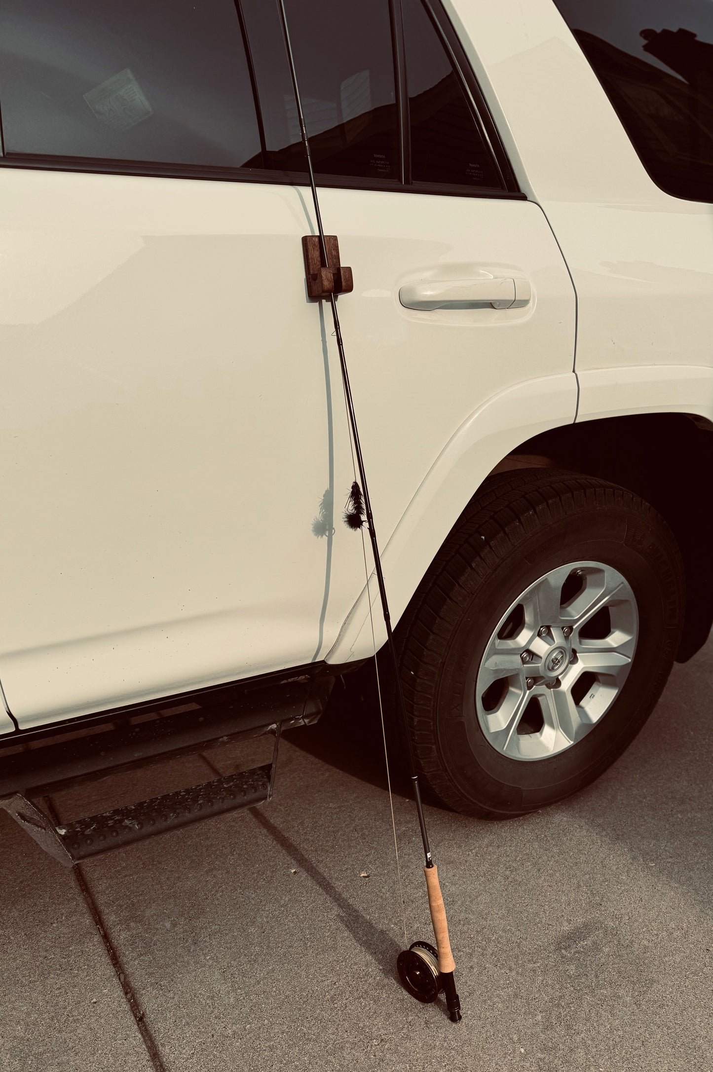 Gearhook on the side of a Toyota 4runner Holding a fly fishing rod between the 2 hooks, protecting it from falling. showcasing its versatility for alternative uses beyond just hanging gear.